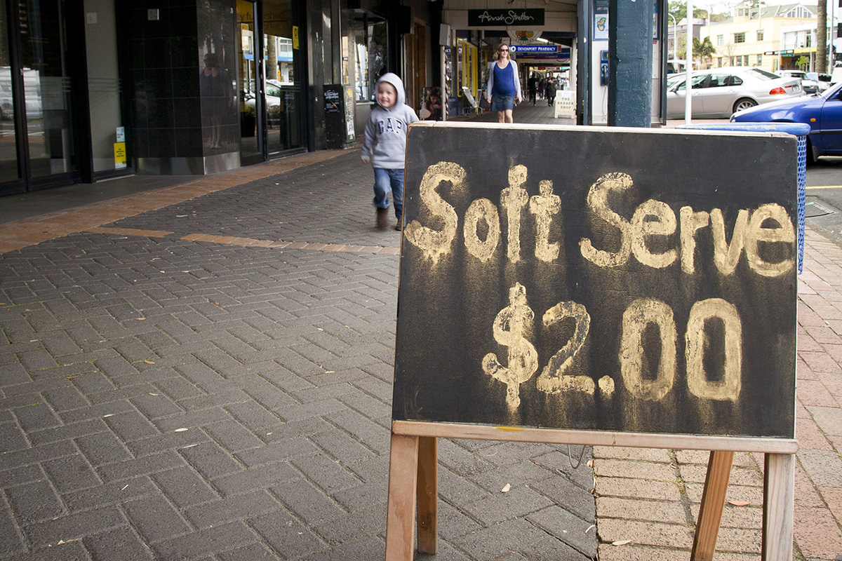 Chalk sign in a street advertising Soft Serve, $2.00. 